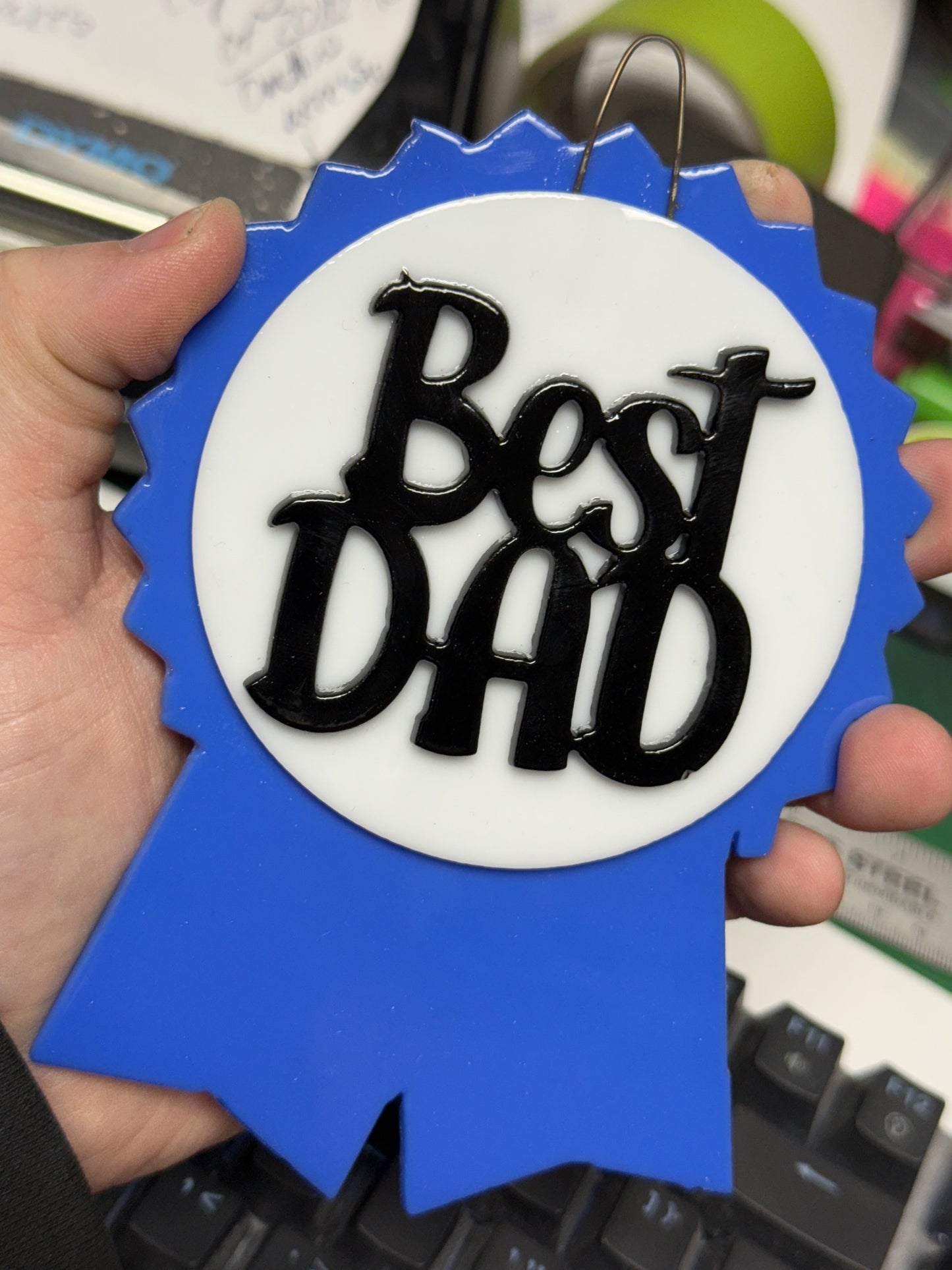Fused glass Father's Day project featuring a blue ribbon, white circle, and black “Best Dad” cutout, tack fused and ready to hang.