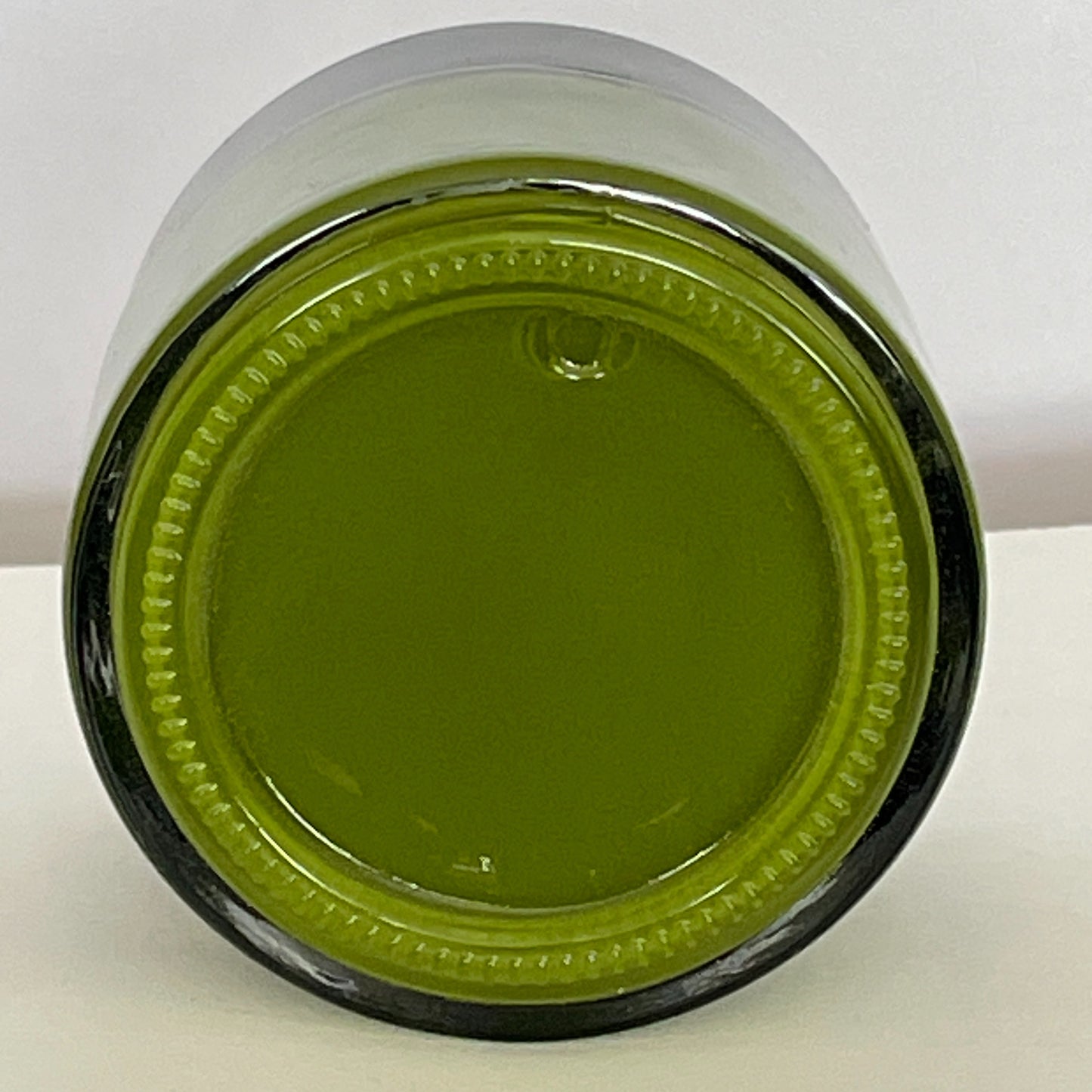 Close-up view from the base of a jar of Brilliant Green screen printing paste, highlighting its vivid green hue and smooth, creamy texture