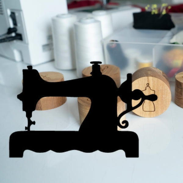 Black Oceanside 96 COE glass vintage sewing machine silhouette placed in front of a fashion design scene, featuring a dressmaker adjusting a mannequin in a creative studio with colorful sketches and sewing supplies.