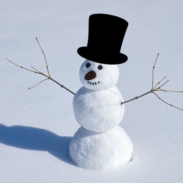 A cheerful snowman made of three snowballs with stick arms, a carrot nose, and coal eyes and mouth, wearing a tall Bullseye COE 90 Glass precut black top hat, standing in a snowy field under clear daylight.