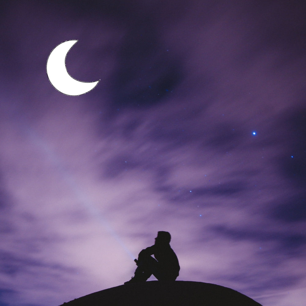 Precut glass shape of a crescent moon in a nigh sky.