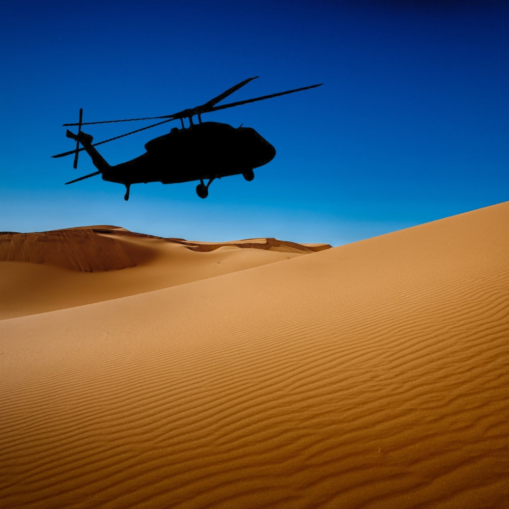 Precut glass shape of a blackhawk helicopter flying over a desert.