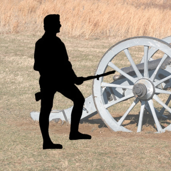 Bullseye COE 90 Glass Precut Silhouette of an American Revolution-era Minuteman with a musket standing beside a historic cannon in a misty field surrounded by grass.