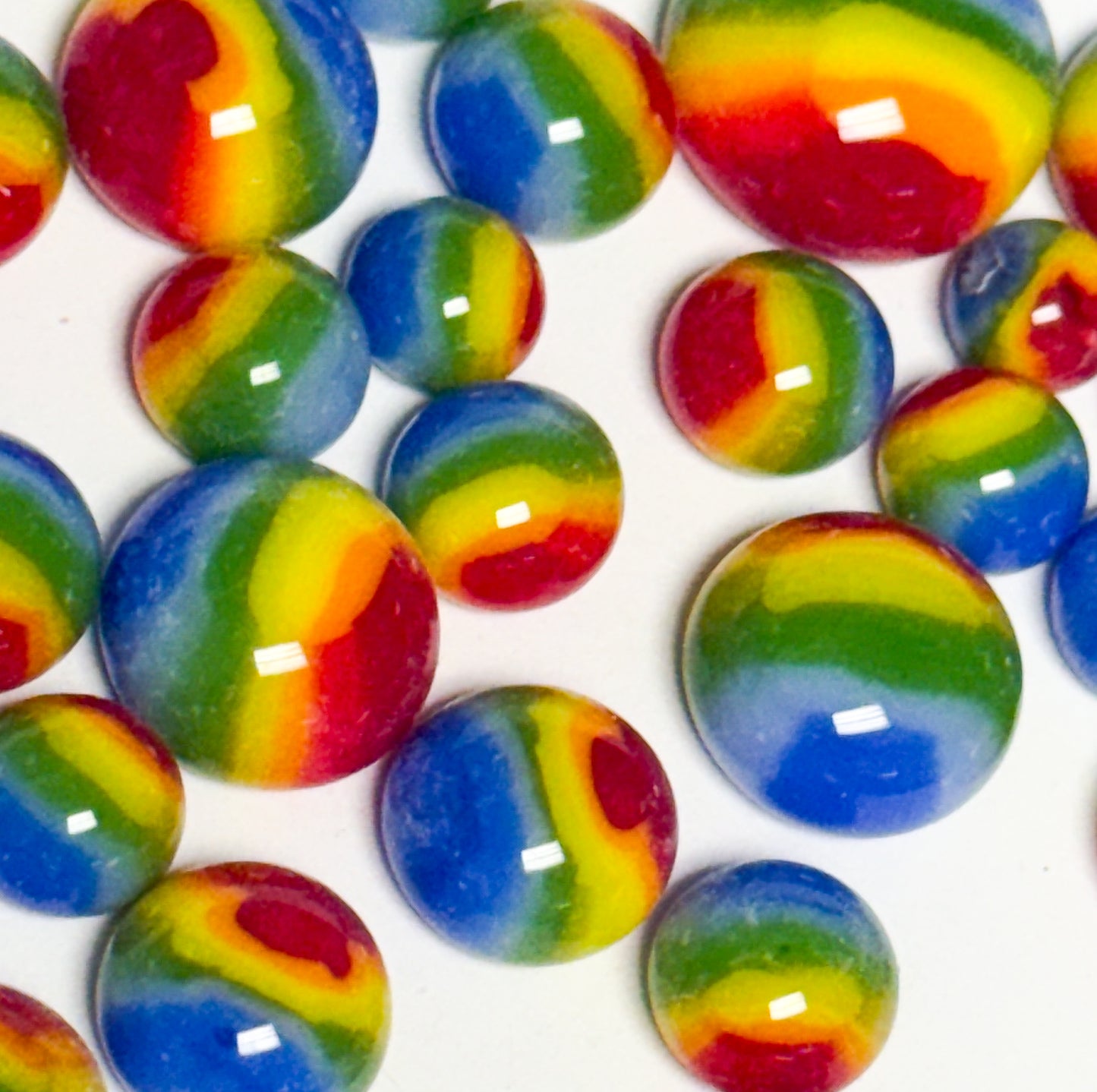Close-up of colorful rainbow COE 96 glass dots showing vibrant red, yellow, green, and blue layers.