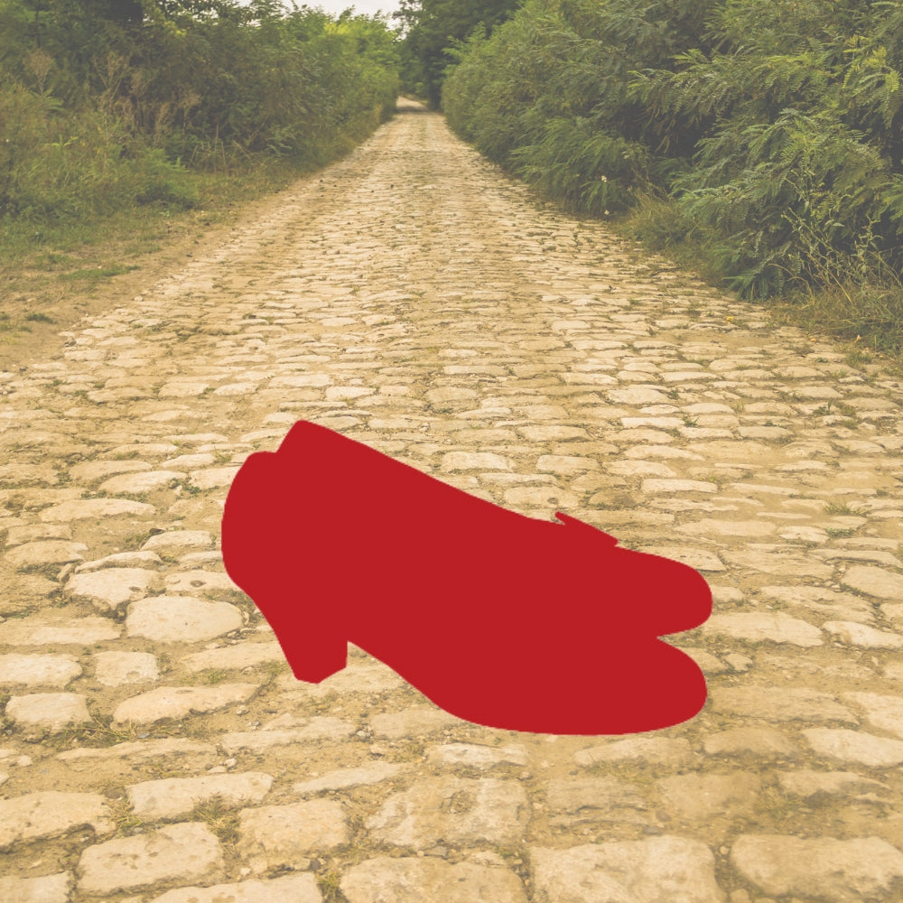 Red glass slipper precut silhouette on a yellow brick road background, symbolizing a fairy tale-inspired fused glass project using COE 96 glass.