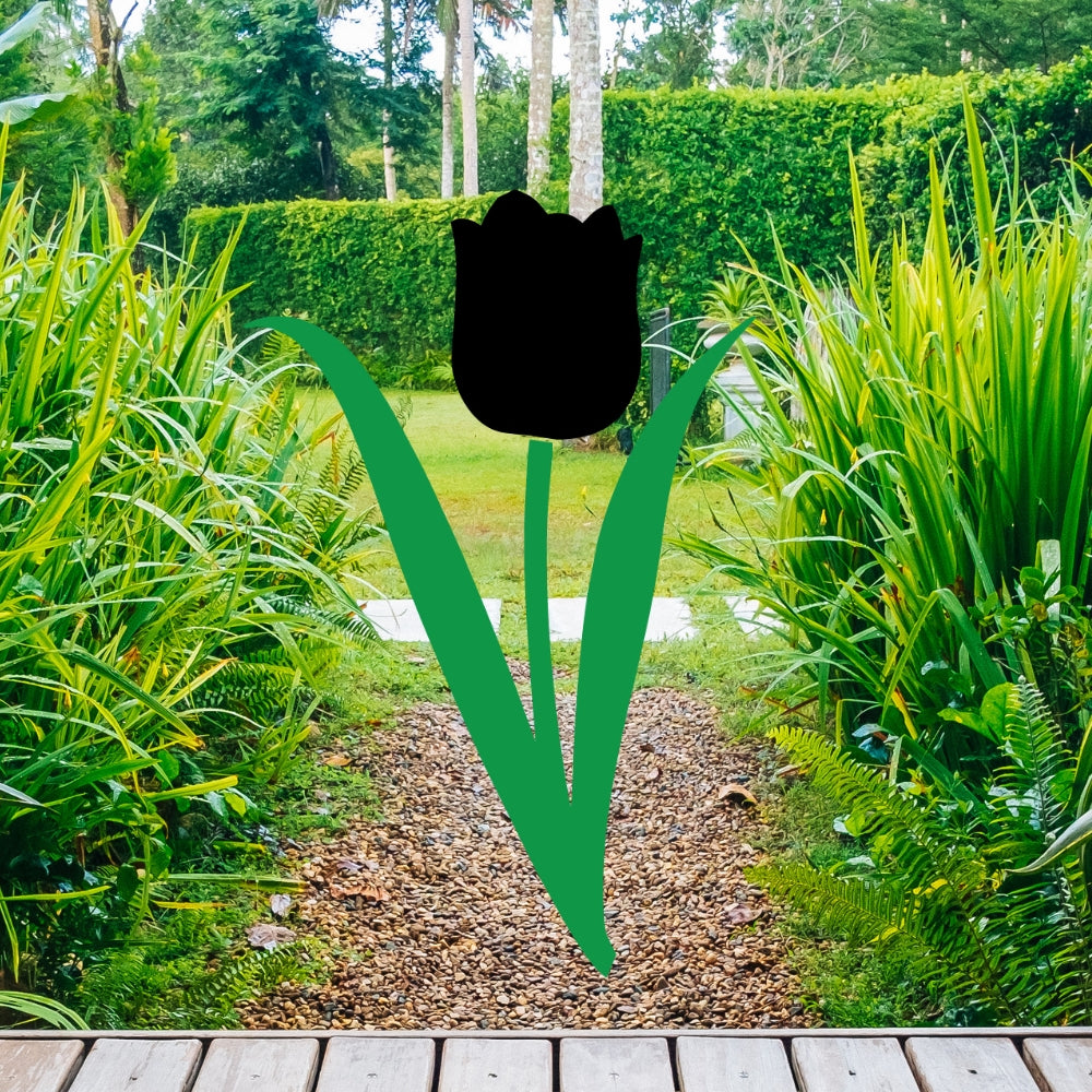 Tulip precut glass shape design with green stem and leaves shown over a garden pathway background, representing a fused glass tulip project for spring glass art, suncatchers, and kiln-fired designs.