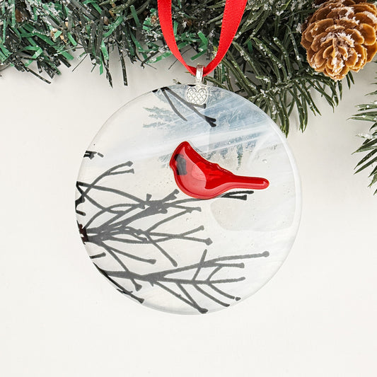 Round Christmas ornament with a red cardinal perched on winter branches, symbolizing love and remembrance.