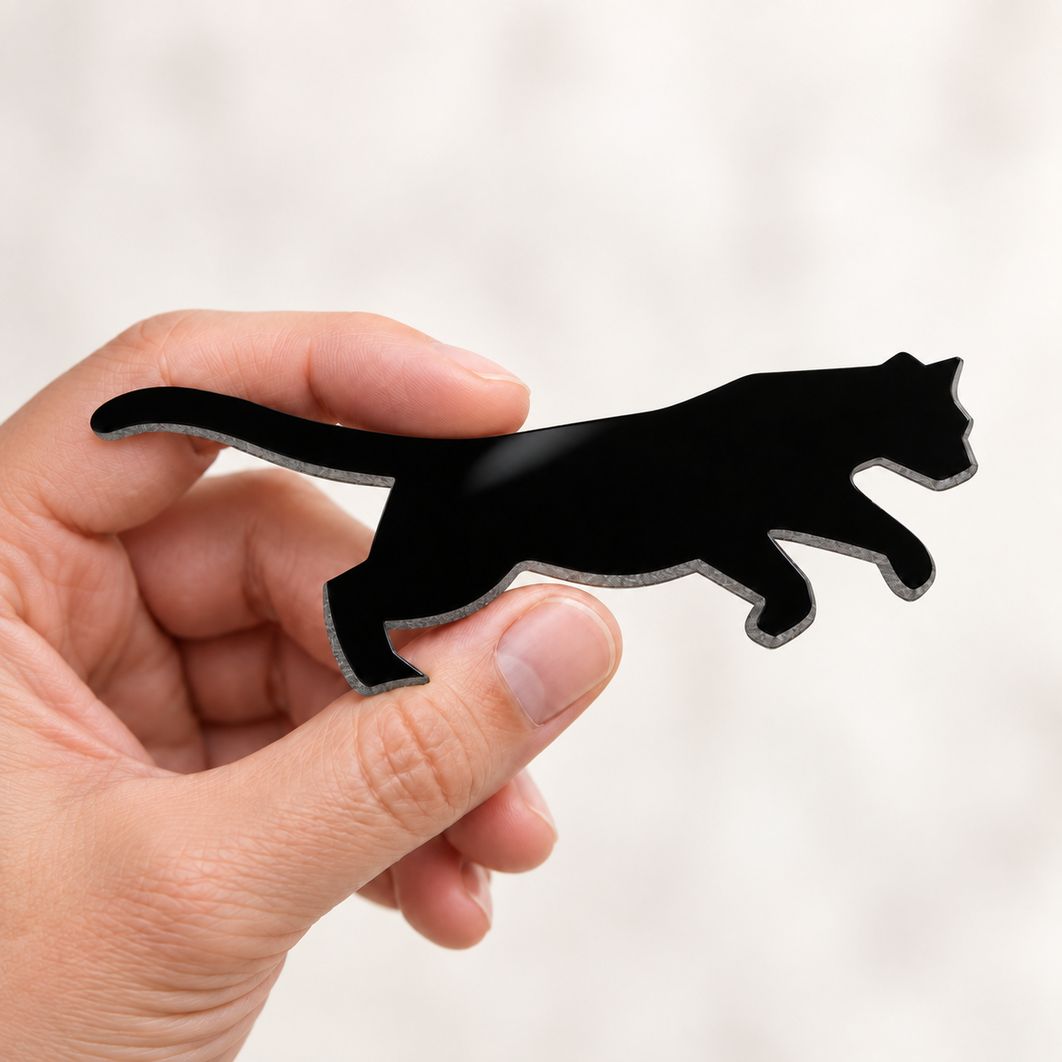 Hand holding a 3-inch black cougar glass precut with glossy surface and ground waterjet-cut edges.
